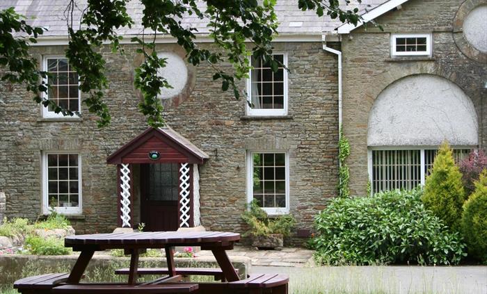 Holiday cottage in Wales that is one half of a Georgian coach house. Lawn and picnic table on lawn in foreground.